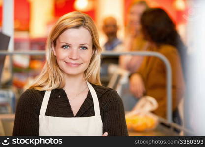 Closeup of a young shop assistant with customer in the background