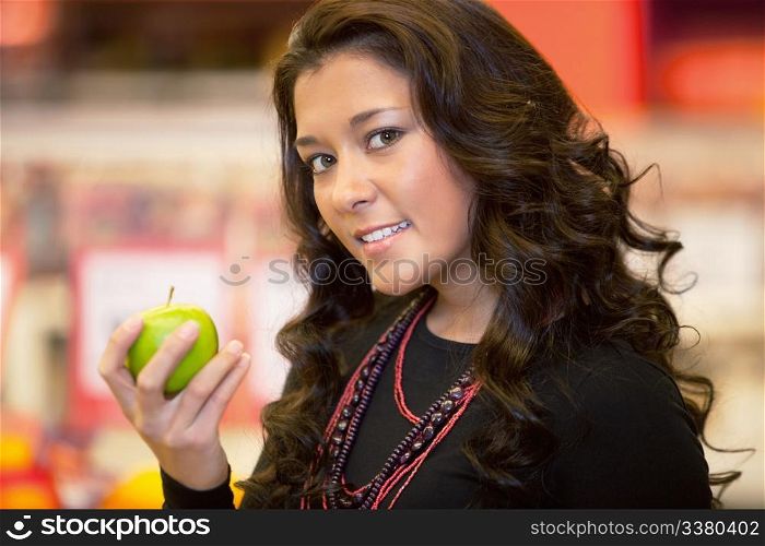 Closeup of a young woman holding apple in the supermarket