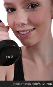 Closeup of a young woman with a dumbbell