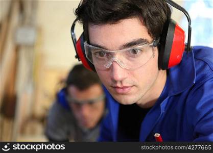 Closeup of a young worker wearing ear defenders