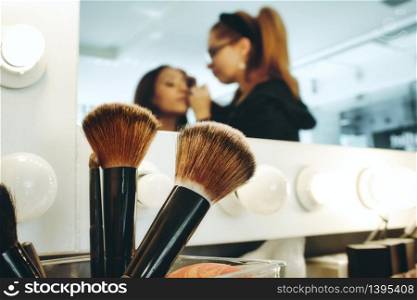 Closeup of accessory brushes with a professional make-up artist in a studio painting a woman's face