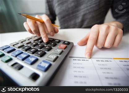 Closeup of accountant counting on calculator and working with table