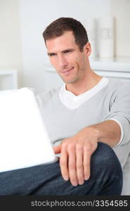 Closeup of adult man sitting on sofa with laptop computer