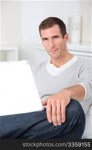 Closeup of adult man sitting on sofa with laptop computer
