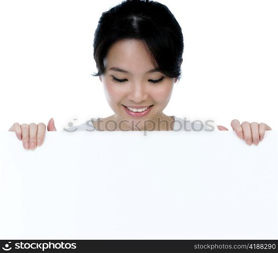 Closeup of an attractive woman holding billboard over white background.