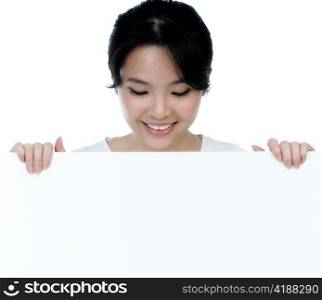 Closeup of an attractive woman holding billboard over white background.