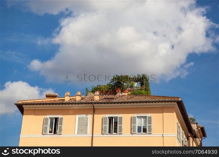 Closeup of ancient building&rsquo;s roof with blue sky and white clouds in Rome City, Italy. Ancient house represented on one of streets in Rome.. Rome City at sunny day