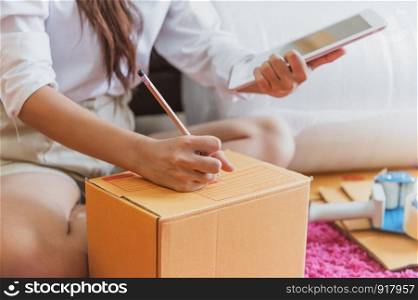 Closeup of Asian business woman hand startup small business entrepreneur SME distribution warehouse with parcel mail box. small owner home office. Online marketing and product packaging and delivery