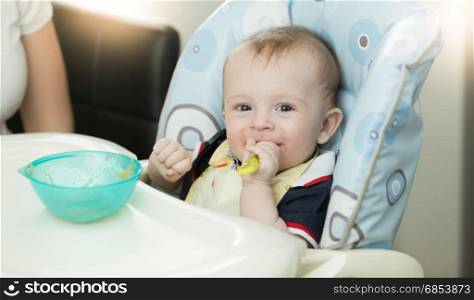 Closeup of baby sitting in highchair and holding spoon