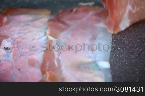 Closeup of bacon strips frying on a grill in slow motion.