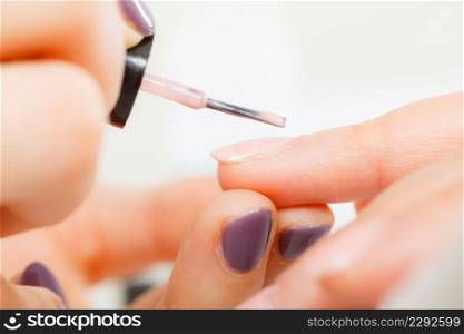 Closeup of beautician painting nails of female client. Woman in beauty spa salon doing manicure. Woman in beauty salon getting manicure done.