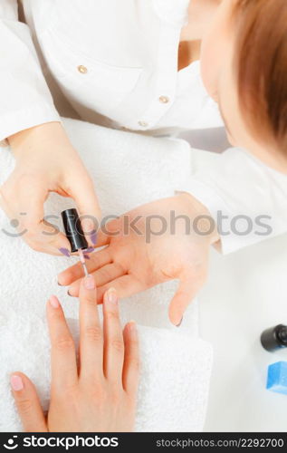 Closeup of beautician painting nails of female client. Woman in beauty spa salon doing manicure. Woman in beauty salon getting manicure done.