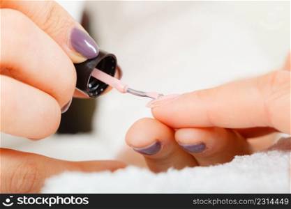 Closeup of beautician painting nails of female client. Woman in beauty spa salon doing manicure. Woman in beauty salon getting manicure done.
