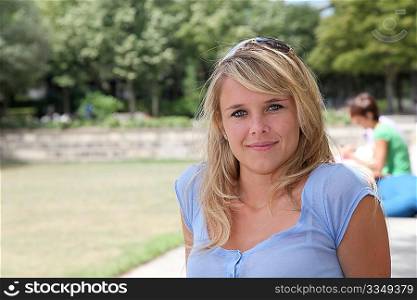 Closeup of beautiful blond woman sitting in a park