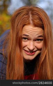 Closeup of beautiful natural redhead woman with smiling eyes looking to the lens.
