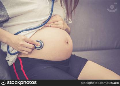 Closeup of beautiful pregnant asian woman to pregnant listening with stethoscope, healthcare concept.