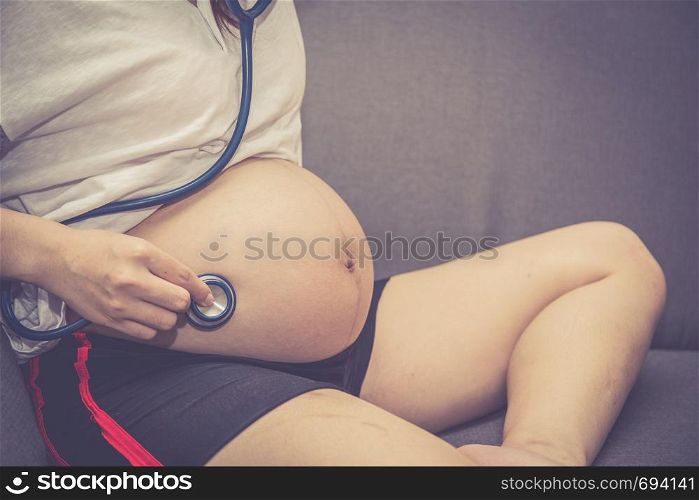 Closeup of beautiful pregnant asian woman to pregnant listening with stethoscope, healthcare concept.