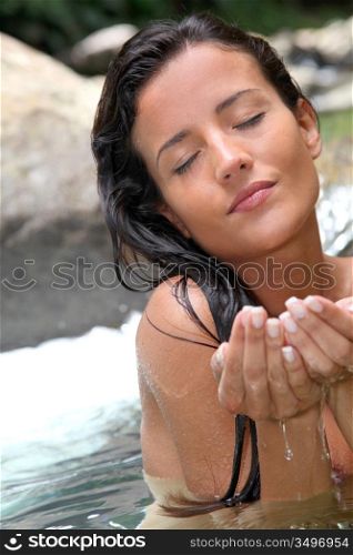 Closeup of beautiful woman taking water from river