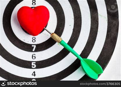 Closeup of black and white target with dart in red valentine heart love symbol as bullseye. Skeet trap shooting sport in valentines day.