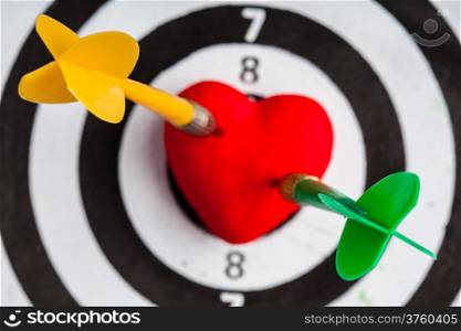 Closeup of black and white target with two dart in red valentine heart love symbol as bullseye. Skeet trap shooting sport in valentines day.