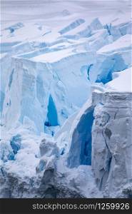 Closeup of bluish chunks of ice and ice cubes with crevices and caves on glacier tongue