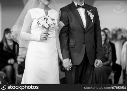Closeup of bride and groom holding hands at wedding ceremony