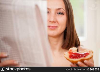 Closeup of brunette woman reading the newspaper while having breakfast at home