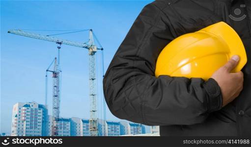 Closeup of builder with yellow helmet at building panorama