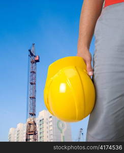 Closeup of builder with yellow helmet on building panorama background