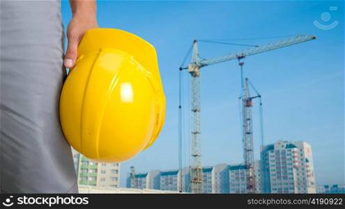 Closeup of builder with yellow helmet on building panorama background