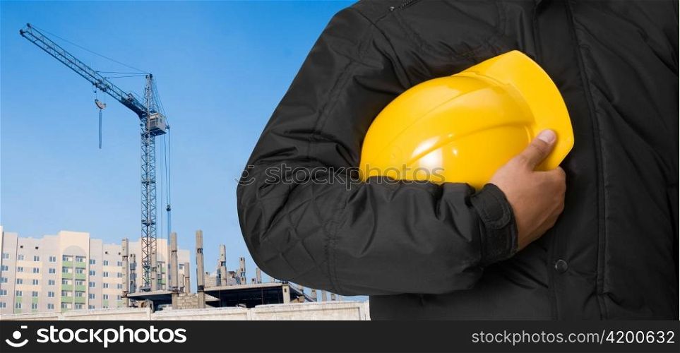 Closeup of builder with yellow helmet on building panorama background
