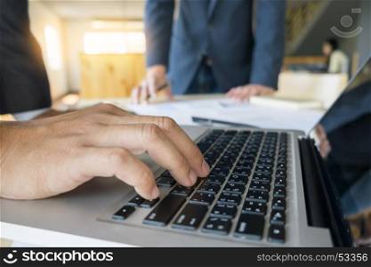 Closeup of businessman is keyboarding on portable net-book, while is sitting in modern office interior. Closely of a successful male entrepreneur is using laptop computer during work day in company.