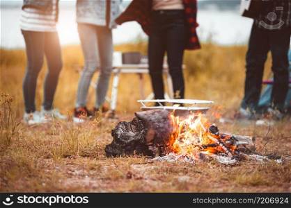 Closeup of campfire with friendship dancing to beat of the music for celebrating in party with mountain meadow and lake view background. People lifestyle and travel vacation. Picnic and camping tent