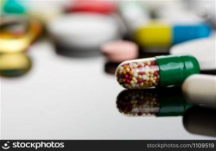 Closeup of capsule against various colorful pills on background