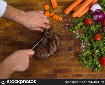 closeup of Chef hands in hotel or restaurant kitchen preparing beef steak with vegetable decoration. closeup of Chef hands preparing beef steak