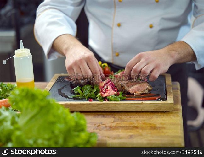 closeup of Chef hands in hotel or restaurant kitchen serving beef steak with vegetable decoration. closeup of Chef hands serving beef steak
