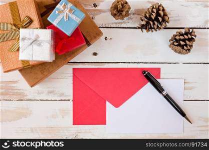 Closeup of Christmas letter and pen over a rustic wooden table with presents and pine cones. Closeup of Christmas letter over a rustic wooden table