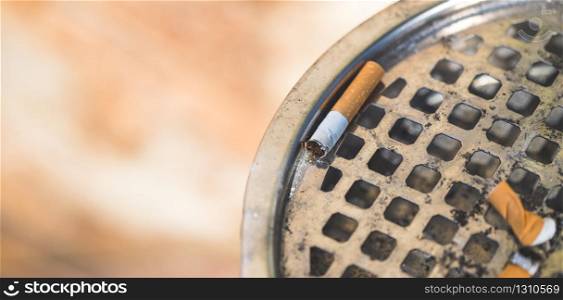 Closeup of cigarette in public ashtray. Extreme closeup, selective focus