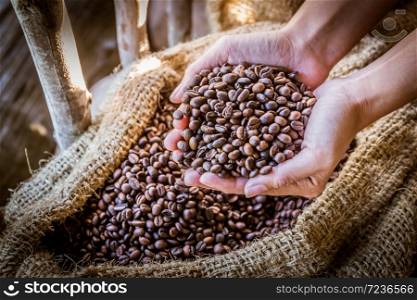Closeup of coffee beans in hand with sunlight in gunny bag