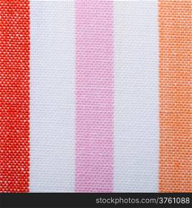 Closeup of colorful red pink orange striped fabric textile as background texture or pattern. Macro.