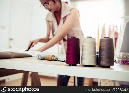 Closeup of colorful thread with fashion designer background in workshop studio. Stylish fashionista woman creating new cloth design collection. Tailoring and sewing People lifestyle and occupation