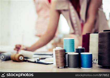 Closeup of colorful thread with fashion designer background in workshop studio. Stylish fashionista woman creating new cloth design collection. Tailoring and sewing People lifestyle and occupation