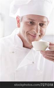 Closeup of confident mature chef smelling food in bowl at restaurant