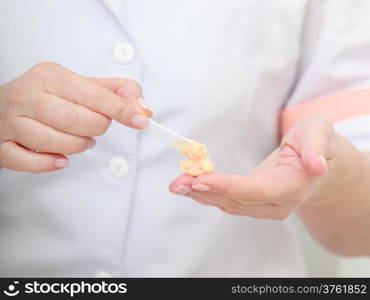 Closeup of cosmetician beautician hands with orange moisturizing cream balm. Skincare. Healthy beauty spa salon.