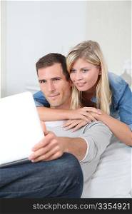 Closeup of couple sitting in sofa surfing on internet