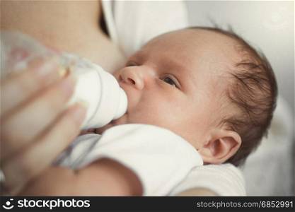 Closeup of cute baby sleeping on mothers hands after eating milk