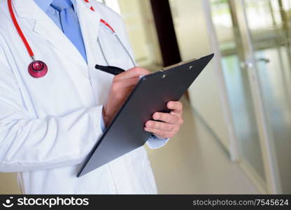 Closeup of doctor writing on clipboard