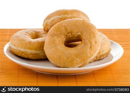 Closeup of donuts on a plate on orange straw mat background.