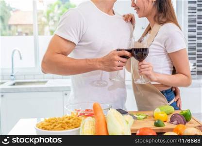 Closeup of drinking wine on happy Asian young married couple hands in home kitchen. Boyfriend and girlfriend cooking together. People lifestyle and romantic relationship concept. Valentines day
