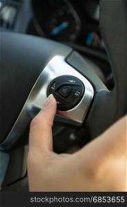 Closeup of driver pressing phone button on car steering wheel